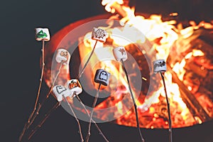 Marshmellows with Halloween pictures over fire. Funny leisure on traditional spooky holiday for children and families.