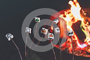 Marshmellows with Halloween pictures over fire. Funny leisure on traditional spooky holiday for children and families.