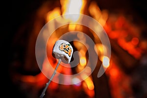 Marshmellows with Halloween pictures over fire. Funny leisure on traditional spooky holiday for children and families.