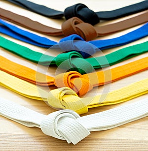 Martial arts colored belts on a wood background.