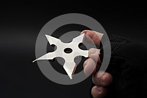 Martial arts skill and traditional Japanese weapon concept with hand in fingerless ninja glove trowing metal star shaped shuriken