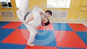 Martial arts. Two athletic men training their aikido skills in the studio. Throwing the opponent on the floor and