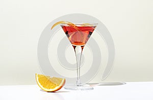Martinez alcoholic cocktail drink with red vermouth, liqueur, orange bitter, zest and ice. Light beige background, hard light,