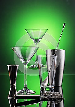 Martini Barware tools on reflective surface and green background