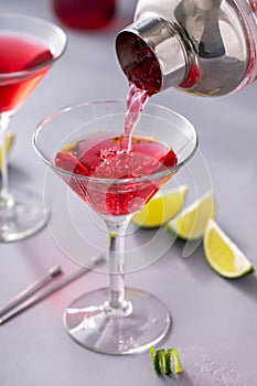 Martini cocktail with cranberry juice garnished with lime twist