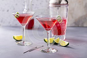 Martini cocktail with cranberry juice garnished with lime twist