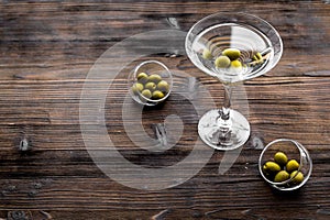 Martini cocktail in glass with olives at the bottom on dark wooden background top view copyspace