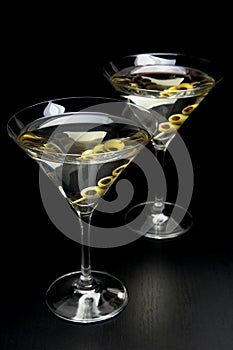 Martini drinks with olives isolated on black table