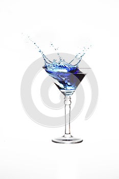 Martini glass with blue water splash in it isolated on white background