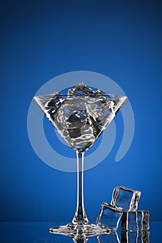 Martini glass with ice on blue