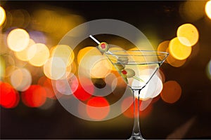 Martini in glass with olives on bokeh background