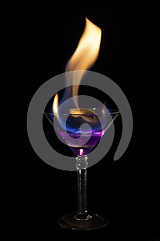 Martini glass with purple drink is on fire and very hot