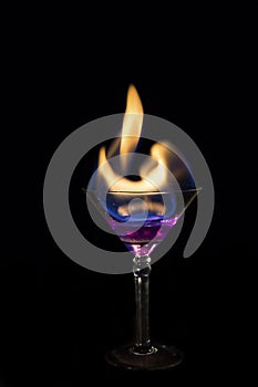 Martini glass with purple drink is on fire and very hot