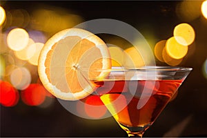 Martini in glass with slice of orange on dark