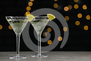 Martini glasses of refreshing cocktails with lemon slices on light grey table, space for text