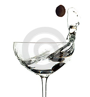 Martini and green olive in glass with splashes isolated on white