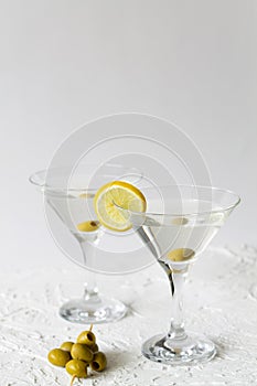 Martini with lemon. Two Martini glasses with cocktail and olives on white background