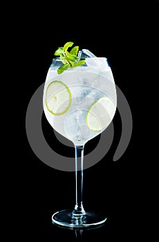 Martini royale cocktail in wine glass with lime and mint isolated on black background