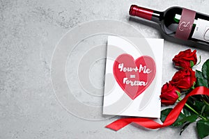 Marvelous message of love with red roses and wine on grey table, flat lay. Space for text