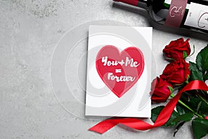 Marvelous message of love with red roses and wine on grey table, flat lay. Space for text