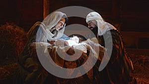 Mary and Joseph caressing baby Jesus in illuminated manger