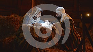 Mary and Joseph caressing baby Jesus in illuminated manger