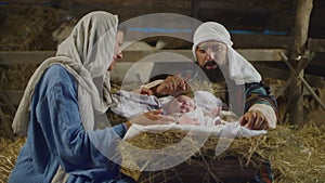 Mary and Joseph taking care of baby Jesus in inn stable