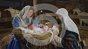 Mary and Joseph taking care of baby Jesus in inn stable