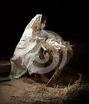 Mary sits in the stable near the manger with the baby