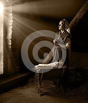 Mary sits in the stable near the manger with the baby