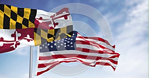 Maryland flag waving in the wind with the american national flag on a clear day