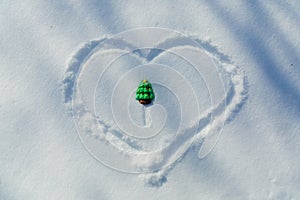 Marzipan candy in the form of a Christmas tree in the snow in a drawn heart