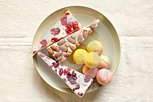 Marzipan fruits and soft nougat with fruits and almond in the plate on white linen tablecloth. Martorana fruit molded a shape of