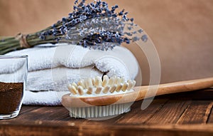 Masage brush, body skin care and coffee natural scrub in glass, white towel and bouquet of dry lavender on dark wooden background photo