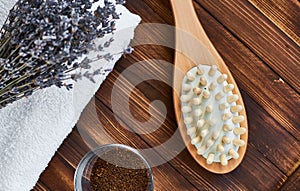 Masage brush, body skin care and coffee natural scrub in glass, white towel and bouquet of dry lavender on dark wooden background photo