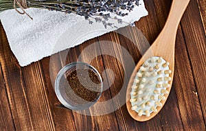 Masage brush, body skin care and coffee natural scrub in glass, white towel and bouquet of dry lavender on dark wooden background