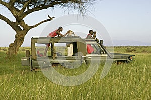 Masai scouts and tourist look for animals from a Landcruiser during a game drive at the Lewa Wildlife Conservancy in North Kenya,