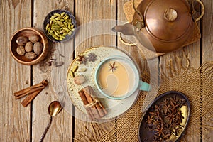Masala chai tea traditional indian drink  with milk and spices on wooden background. Top view from above