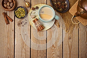 Masala chai tea traditional indian drink  with milk and spices on wooden background. Top view from above