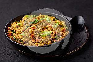 Masala Egg Bhurji or Muttai Podimas in black bowl on slate table top. Anda Bhurji is indian cuisine scrambled eggs dish