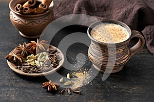 Masala pulled tea chai latte hot Indian sweet milk spiced drink, cinnamon stick, cloves, fresh spices and herbs blend