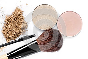 Mascara, beige powder for face, eye shadow and makeup brush on white background