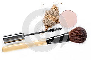 Mascara, beige powder for face, eye shadow and makeup brush on white background