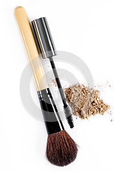 Mascara, beige powder for face and makeup brush on white background