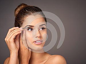 Mascara is an instant confidence booster. a beautiful young model applying mascara to her lashes in studio.