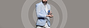Masculine perfume, bearded man in a suit. Male holding up bottle of perfume. Man perfume, fragrance. Perfume or cologne