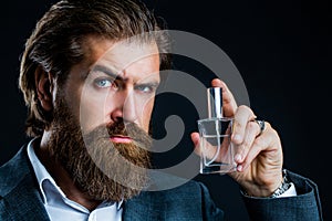 Masculine perfumery, bearded man in a suit. Male holding up bottle of perfume. Man perfume, fragrance. Perfume or