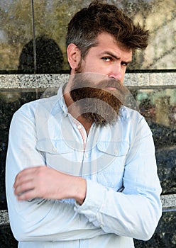 Masculinity concept. Guy looks suspicious. Hipster with tousled hair hold arms crossed on chest. Man with beard and