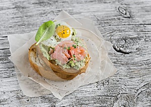 Mashed avocado sandwich with smoked salmon and fried quail egg. A delicious breakfast or snack.