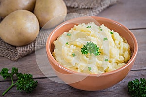 Mashed potato in bowl and fresh potatoes on sackcloth